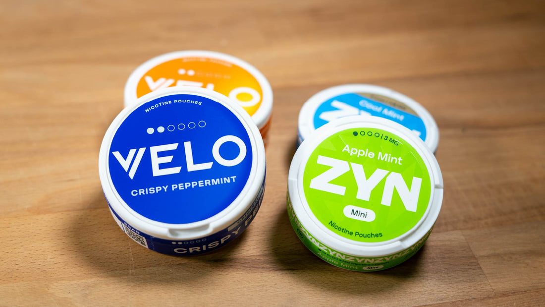 Four containers of nicotine pouches on a wooden surface.