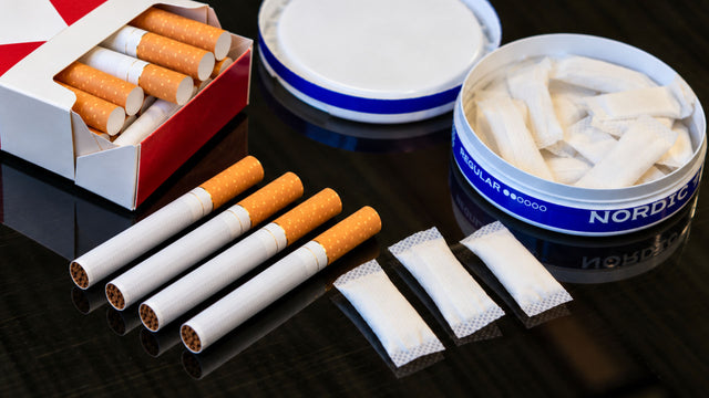 Cigarettes and tobacco pouches arranged on a dark surface.